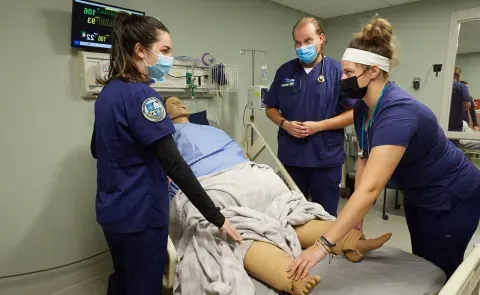 Nursing students stand around a patient simulator in UNE's Interprofessional Simulation and Innovation Center